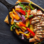 Easy Sheet Pan Chicken Fajitas with colorful bell peppers and onions on a baking sheet.